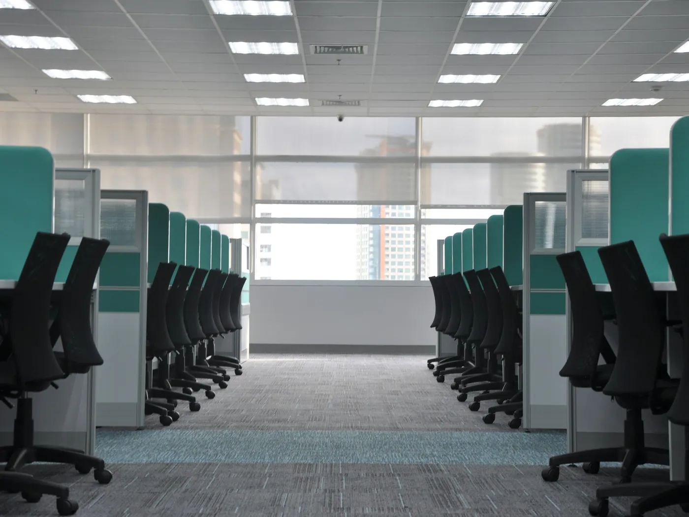 A tidy open-plan office with rows of desks and chairs under bright ceiling lights