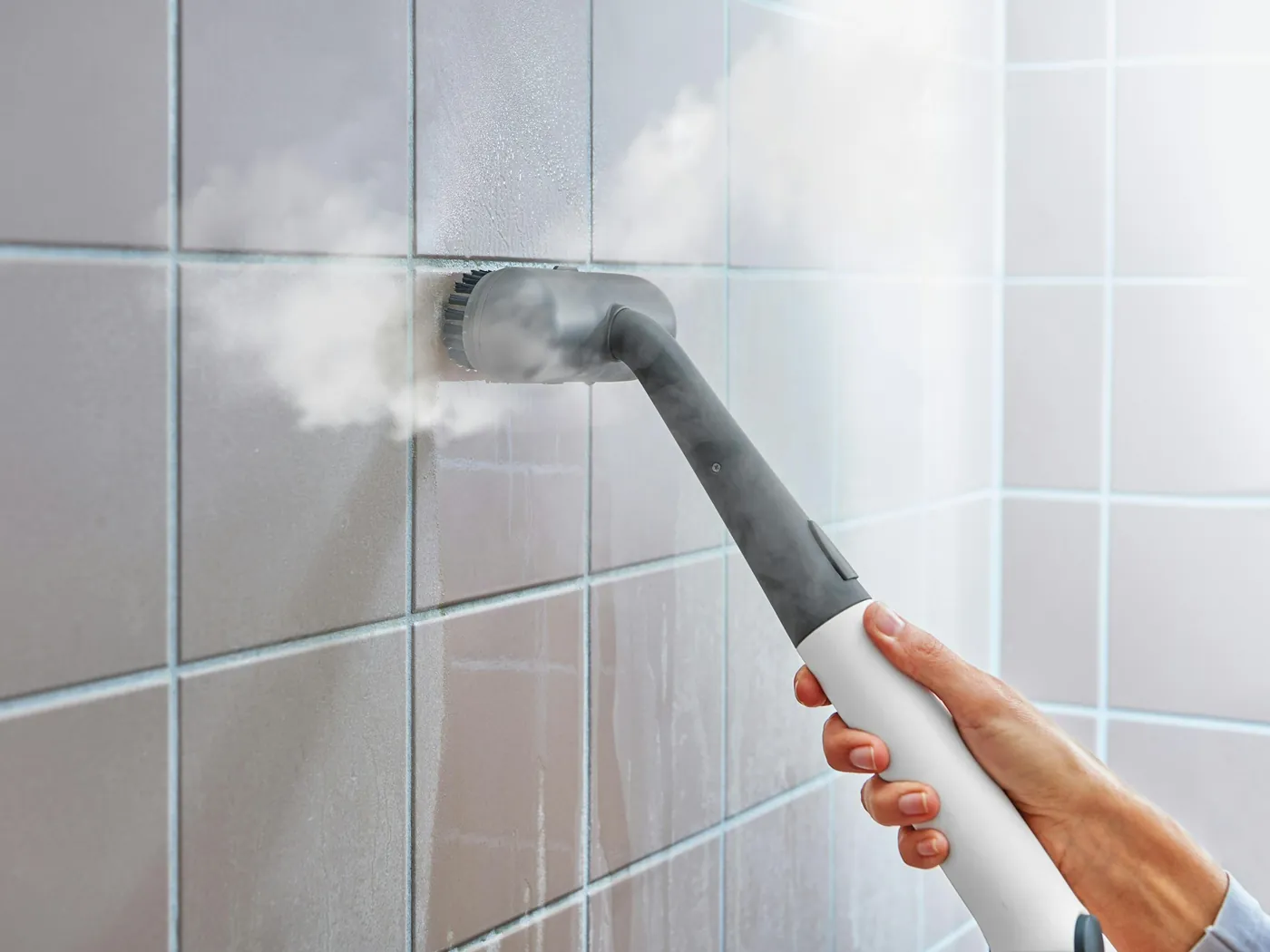 A steam cleaner being used on a tiled wall